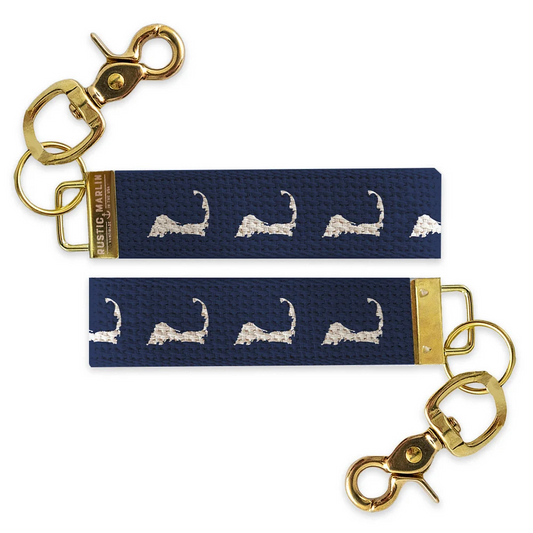 Navy blue Cape Cod wristlet keychain with repeating white Massachusetts Cape Cod silhouettes and gold-tone hardware.